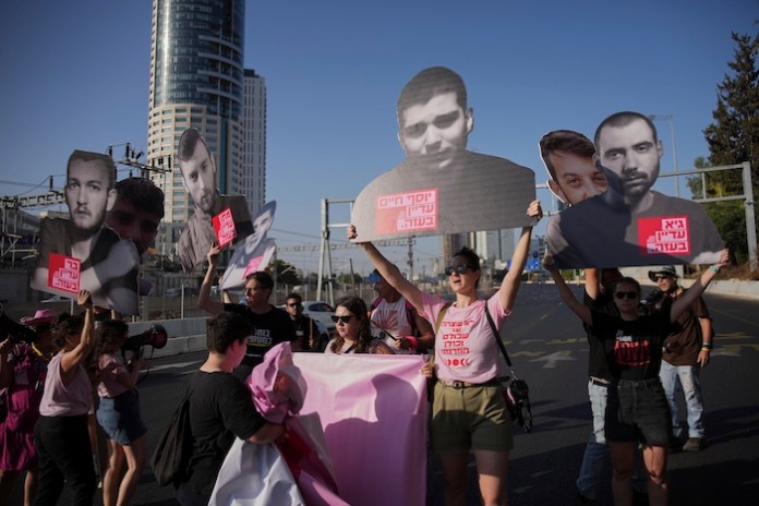 Demonstrators block a road during a protest demanding the immediate release of hostages held by Hamas and calling for the Israeli government to reverse its decision to take over Gaza City and other areas in the Gaza Strip, in Tel Aviv, Israel, Tuesday, Aug. 19, 2025. (AP Photo/Ohad Zwigenberg)