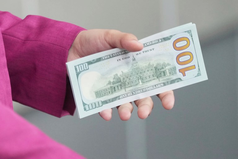An employee holds U.S dollars banknotes at a money changer in Jakarta, Indonesia, Tuesday, April 8, 2025.