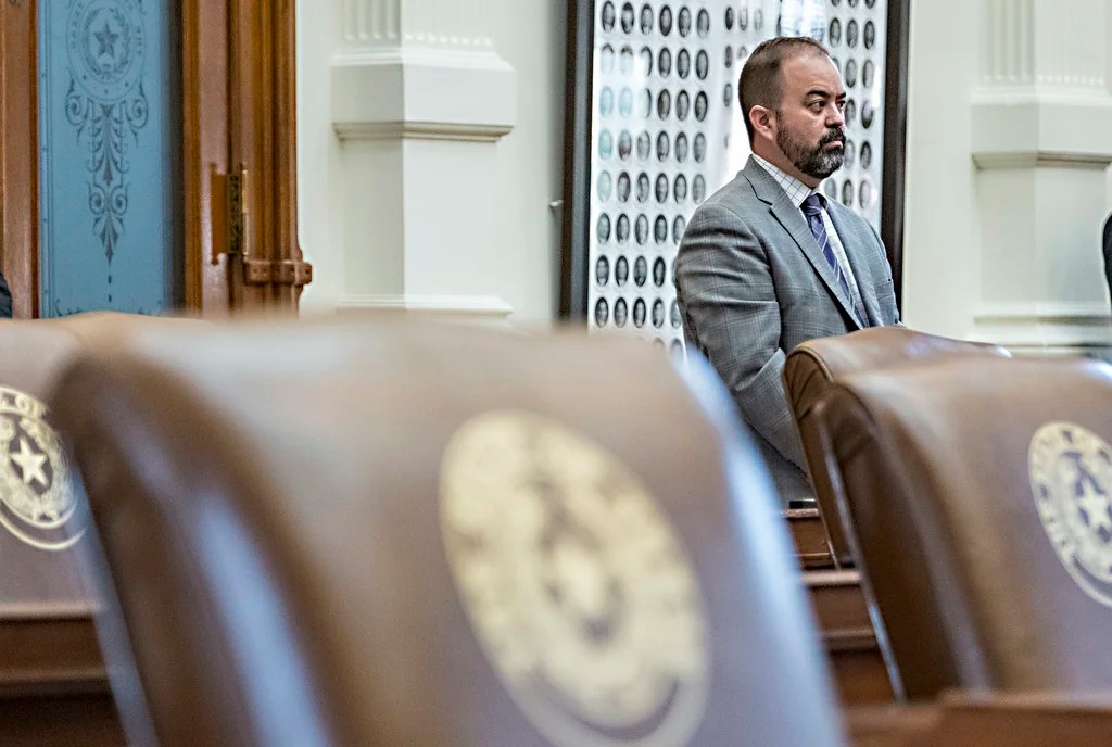Texas House Rep. Joe Moody, D - El Paso, stands at the back of the House Chambers with empty chairs belonging to House Democrats protesting a redistricting map at the State Capitol, Tuesday, Aug. 5, 2025, in Austin, Texas. (AP Photo/Rodolfo Gonzalez)
