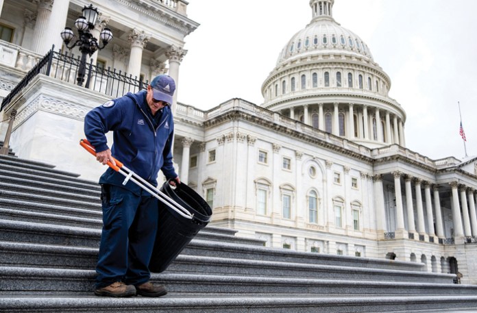 An Architect of the Capitol worker picks up trash on the House steps of the U.S. Capitol after the House passed the One Big Beautiful Bill Act on May 22. (Tom Williams/CQ Roll Call via AP)