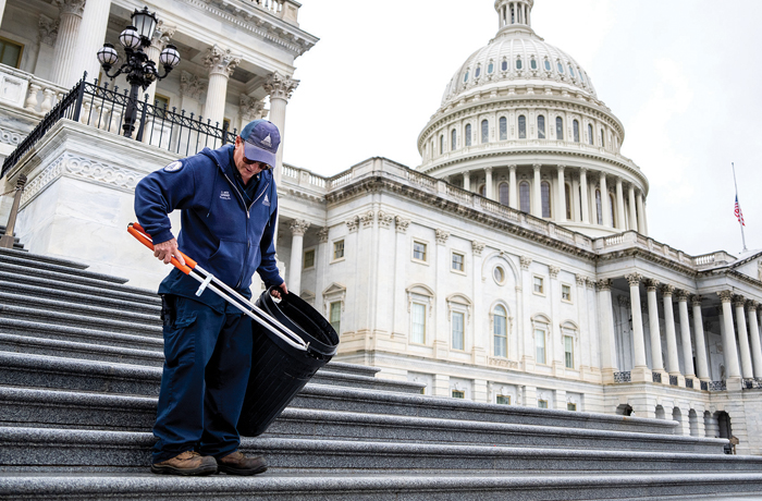 An Architect of the Capitol worker picks up trash on the House steps of the U.S. Capitol after the House passed the One Big Beautiful Bill Act on May 22. (Tom Williams/CQ Roll Call via AP)