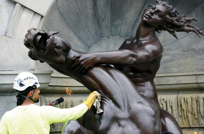 A worker polishes a statue in the Court of Neptune fountain outside of the Library of Congress. (Bryan Olin Dozier/NurPhoto via AP)