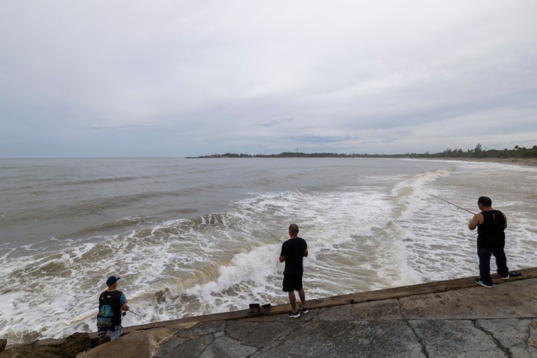 People fish along the shore in Arecibo, Puerto Rico, as Hurricane Erin brings rains to the island, Sunday, Aug. 17, 2025.