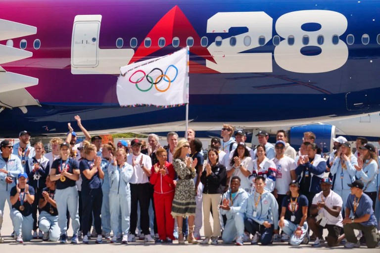 Los Angeles Mayor Karen Bass, Team USA athletes, LA28 organizing committee members and the United States Olympic & Paralympic Committee, Delta executives and special guests take a picture with the official Olympic flag.