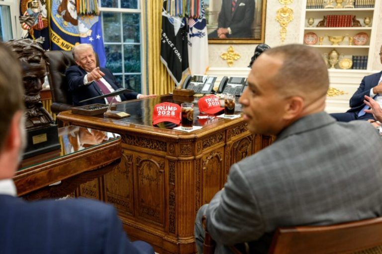 Donald Trump points to Trump 2028 hats.