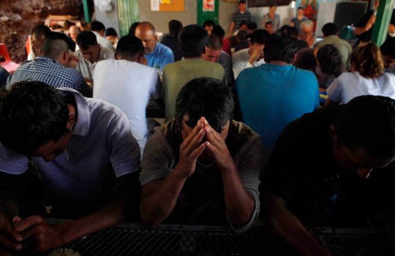 Deportees pray as they gather for breakfast.