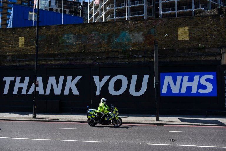 A Police Officer rides past a mural with a message saying 'Thank you NHS.'