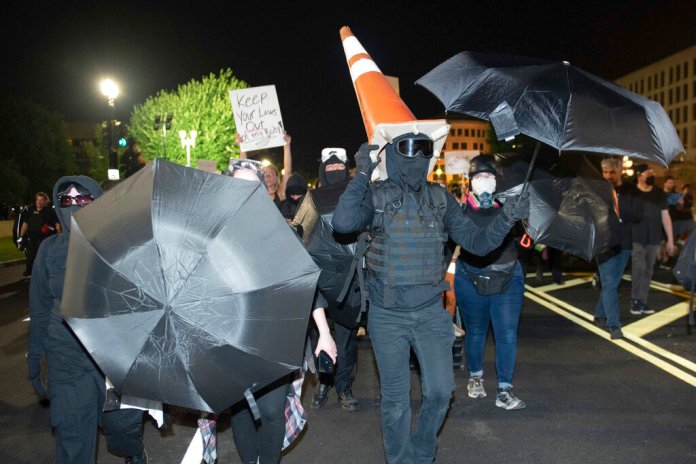 An antifa member wears a road cone as a hat as they lead a group of abortion protesters on Friday, June 24, 2022, in Washington.
