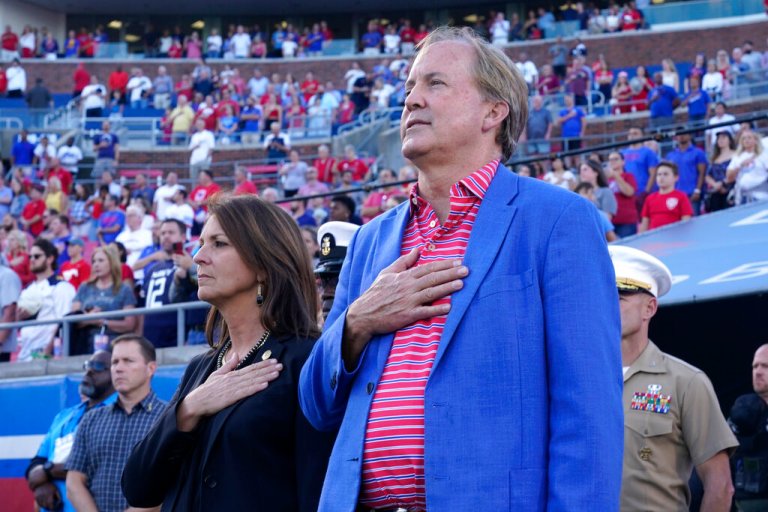Ken Paxton and his wife at the time, Angela, pledge allegiance at an NCAA college football game in 2022.