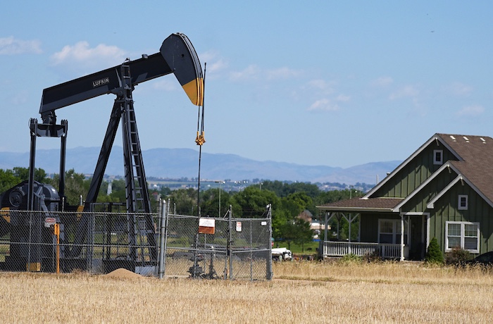 FILE - A pumpjack works on a pad near a housing development July 4, 2024, in Dacono, Colo.