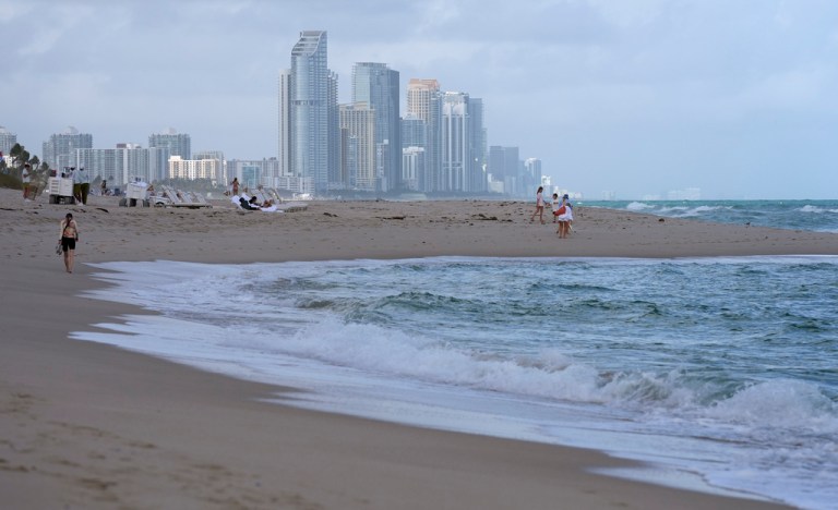 People walk along the beach in Surfside, Florida.