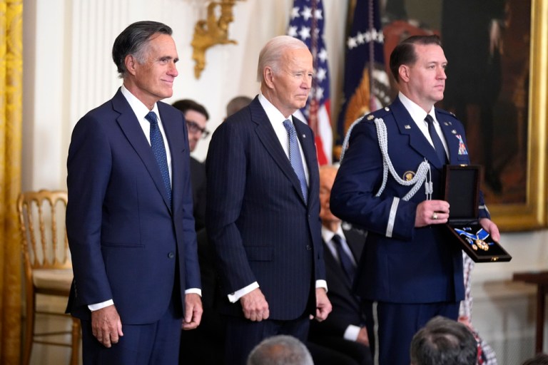 President Joe Biden stands next to former Republican Utah Sen. Mitt Romney.
