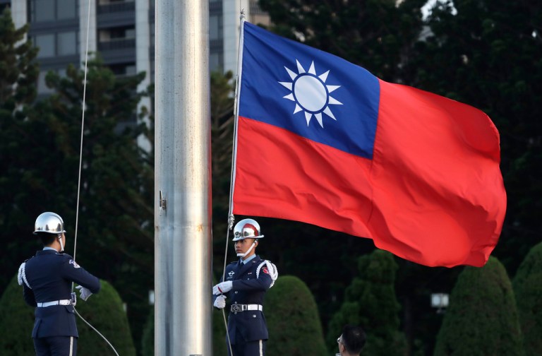 Two soldiers lower the Taiwan national flag during the daily flag ceremony at the Chiang Kai-shek Memorial Hall.
