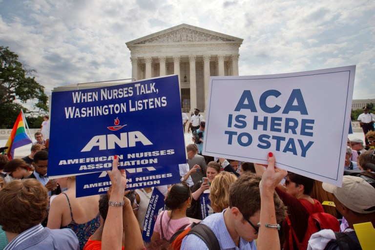 FILE - Supporters of the Affordable Care Act hold up signs as the opinion for health care is reported outside of the Supreme Court in Washington, June 25, 2015. The Supreme Court on Thursday upheld the nationwide tax subsidies under President Barack Obama's health care overhaul, in a ruling that preserves health insurance for millions of Americans.