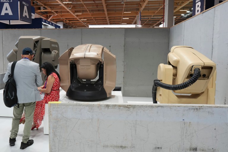 Visitors stand by Iron Beam Laser Weapon System on the Rafael stand in the Israeli pavilion at the Paris Air Show.