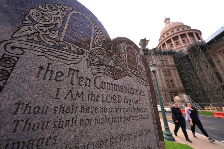 A granite Ten Commandments monument stands on the ground.