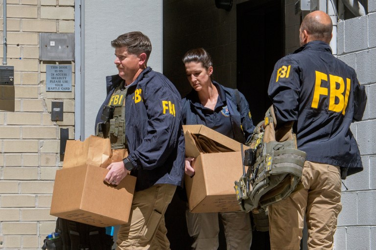 FBI agents carry boxes from former National Security Advisor John Bolton's office in Washington, Friday, Aug. 22, 2025.