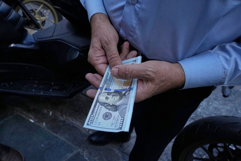 A street money exchanger poses for a photo without showing his face as he holds a U.S. banknotes at Ferdowsi square.