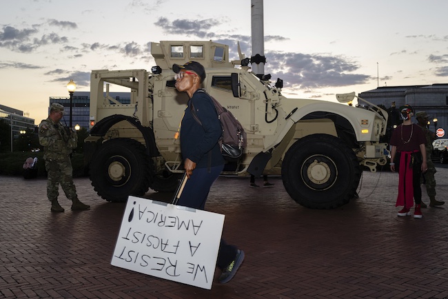 A protester walks past members of the D.C. National Guard and a Mine Resistant Ambush Protected vehicle at Union Station.