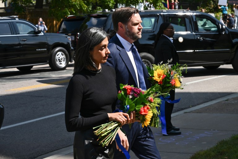 JD Vance and his wife Usha Vance stand outside a vigil holding flowers