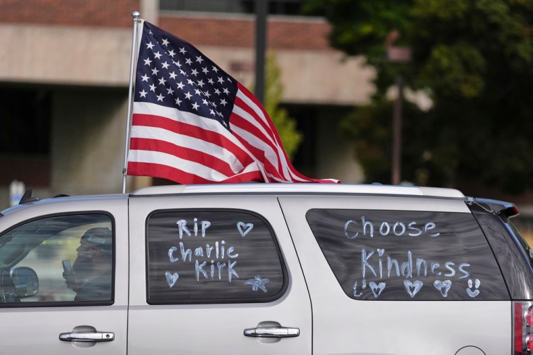 A vehicle marked with messages on its windows in tribute to Turning Point USA CEO and co-founder Charlie Kirk and carrying an American flag.