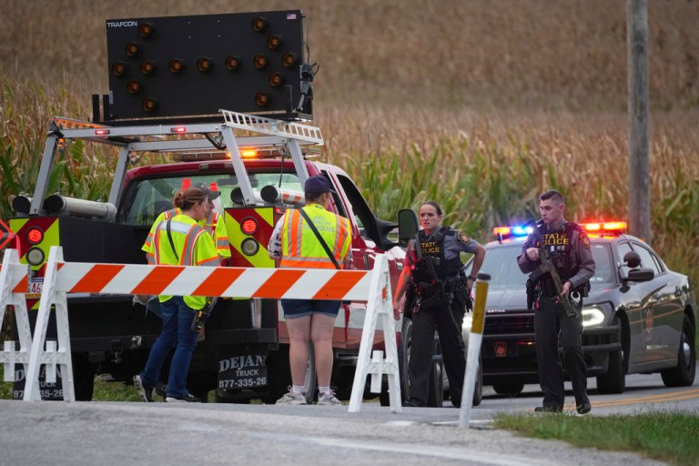 Pennsylvania state police troopers and emergency workers block a road.