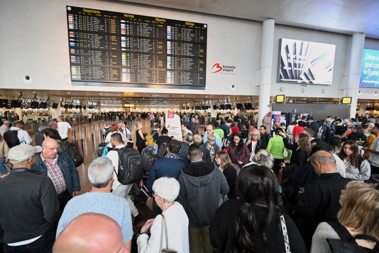People stand in front of a departure board after a cyber attack caused delays at Brussels International Airport in Zaventem, Belgium, Saturday, Sept. 20, 2025. (AP Photo/Harry Nakos)