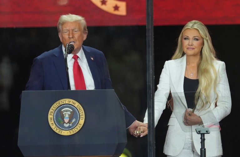 President Donald Trump and Erika Kirk hold hands.
