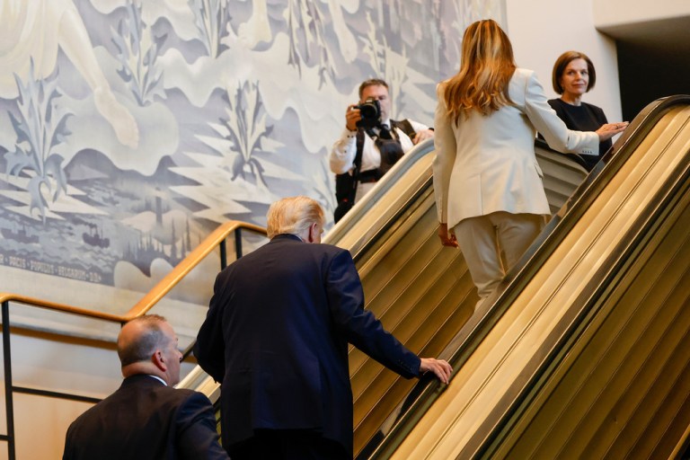 President Donald Trump and first lady Melania Trump walk up the escalator after it stalled as he rode up to the General Assembly Hall.