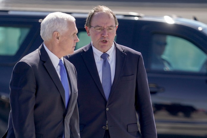 FILE - Vice President Mike Pence talks to Tom Tiffany at the airport after visiting the GE Healthcare manufacturing facility April 21, 2020, in Madison, Wisconsin. 