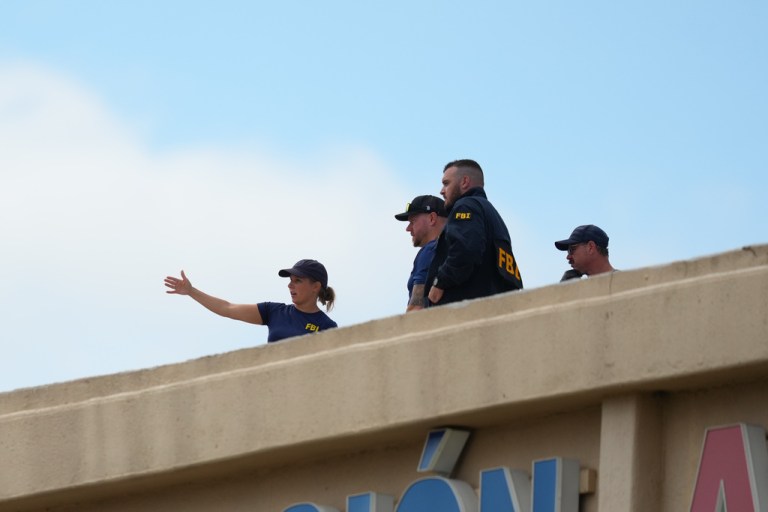 Law enforcement agents look around the roof of an apartment building.