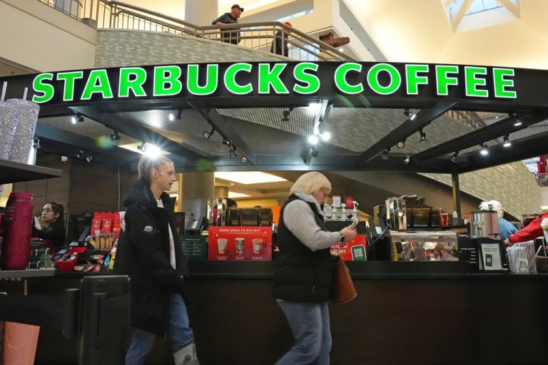 Customers walk by a Starbucks kiosk.