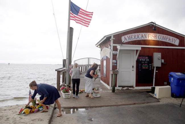 People place flowers in front of the American Fish Company.