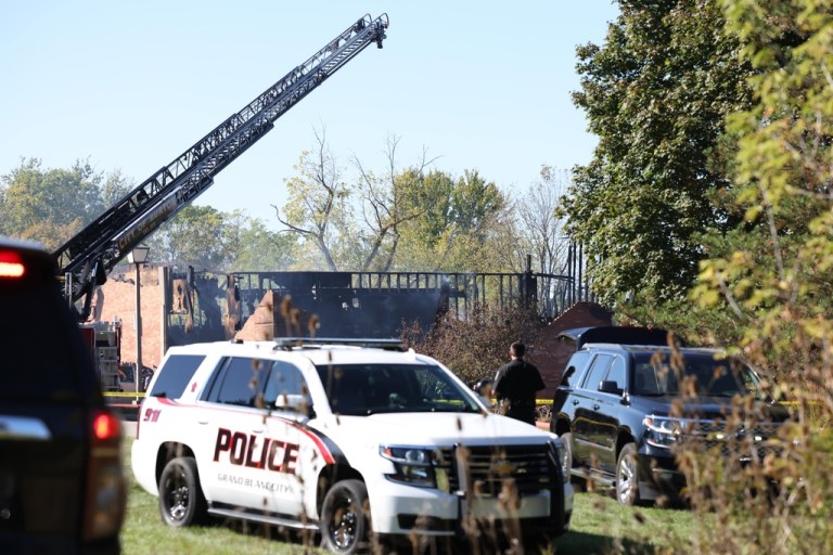 Fire and law enforcement officers stand outside.