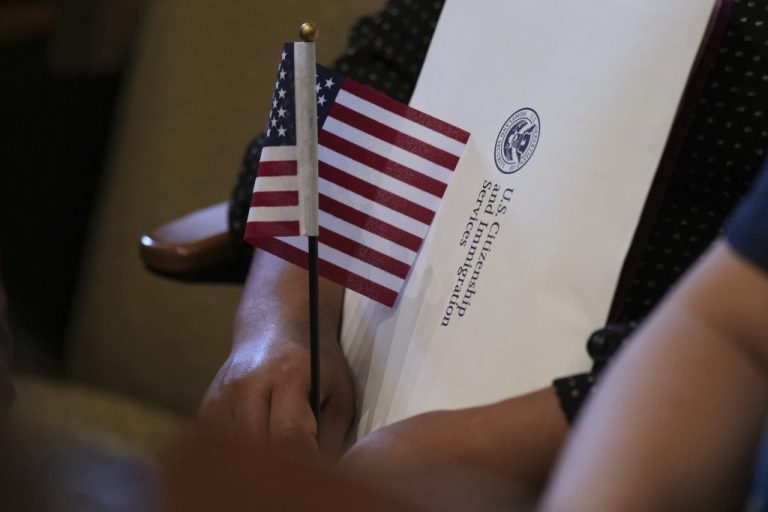 A woman clutches a U.S. flag as she and applicants from 20 countries prepare to take the oath of citizenship in commemoration of Independence Day during a Naturalization Ceremony in San Antonio, Thursday, July 3, 2025.