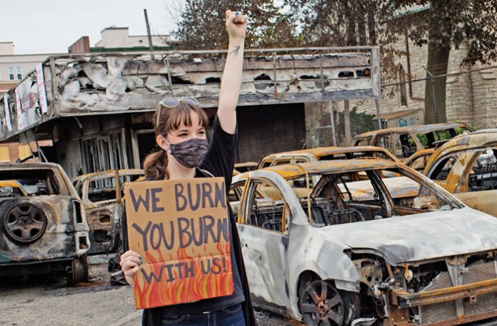 A Black Lives Matter supporter poses for a photograph in a Kenosha, Wisconsin, car dealership burnt by rioters, Sept. 1, 2020. (Andrew Lichtenstein/Corbis /Getty)