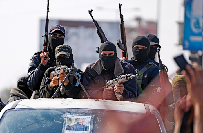 Armed members of Hamas's Izzedine al Qassam Brigades ride in the back of a truck.