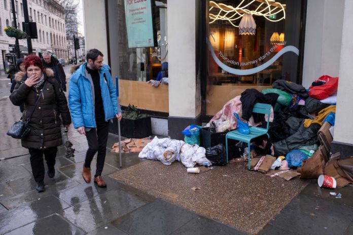 Pile of duvets, sleeping bags, blankets and cardboard, used by homeless people on the pavement while people pass by on the Strand on 28th January 2025 in London, United Kingdom. The scene is illustrative of the social disparity in the UK with some people who live in relative wealth in comparison to others. (photo by Mike Kemp/In Pictures via Getty Images)