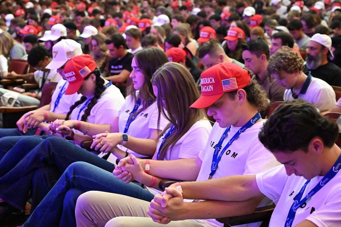 Attendees pray during an "American Comeback Tour" stop hosted by Turning Point USA in Burruss Hall at Virgina Tech university in Blacksburg, Virginia, on September 24, 2025. The event is being held two weeks after the killing of right-wing activist and co-founder of Turning Point USA Charlie Kirk during an "American Comeback Tour" stop in Orem, Utah on September 10. (Photo by Alex WROBLEWSKI / AFP) (Photo by ALEX WROBLEWSKI/AFP via Getty Images)