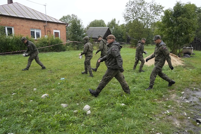 Territorial defense officers pick up debris from the destroyed roof of a house, after Russian drones violated Polish airspace during an attack on Ukraine, in Wyryki near Lublin, Poland, Thursday, Sept. 11, 2025. (AP Photo/Czarek Sokolowski)