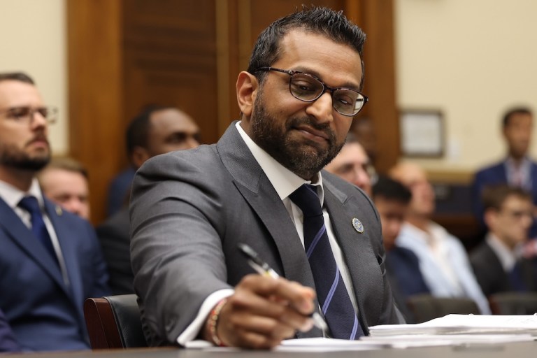 FBI Director Kash Patel writes with a pen.