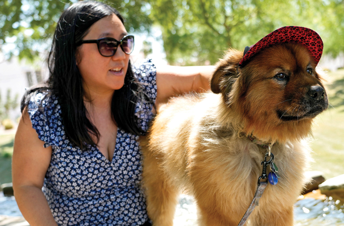 Terry Tang sits with her dog, Teddy, as he dons a doggie cap at a park in Phoenix. (Matt York/AP)