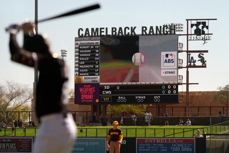 Baseball players looks on at score board with an electronic pitch tracker