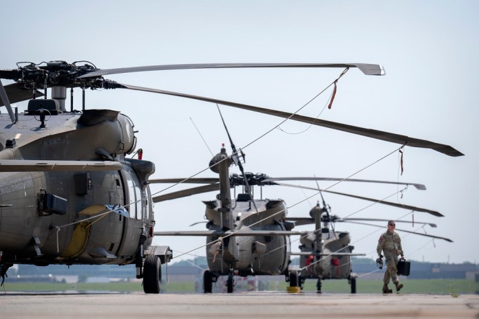 A crew member walks past U.S. Army UH-60M Black Hawk helicopters.