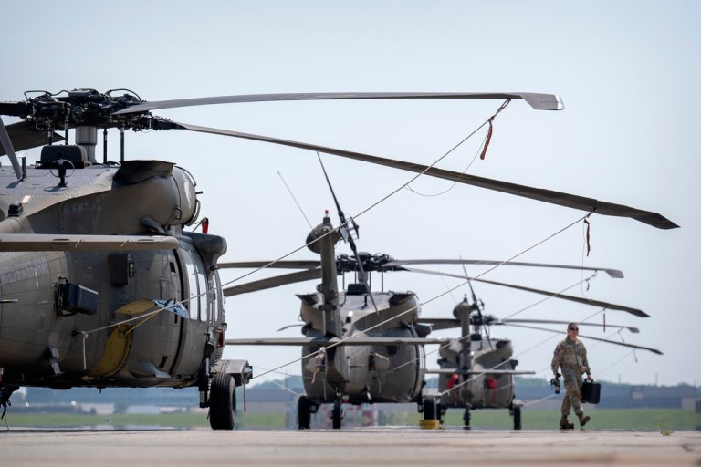 A crew member walks past U.S. Army UH-60M Black Hawk helicopters that will participate in a military parade commemorating the Army's 250th anniversary and coinciding with President Donald Trump's 79th birthday, at Joint Base Andrews, Maryland.