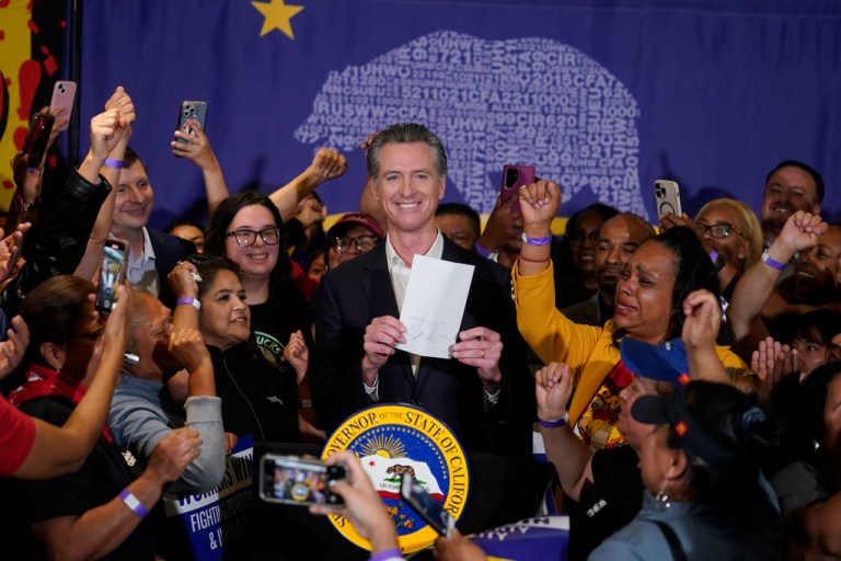 Gov. Gavin Newsom (D-CA) signs the fast-food bill surrounded by fast-food workers.