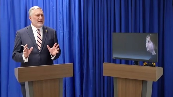 man and tv screen at podium