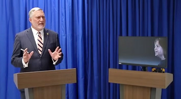 man and tv screen at podium