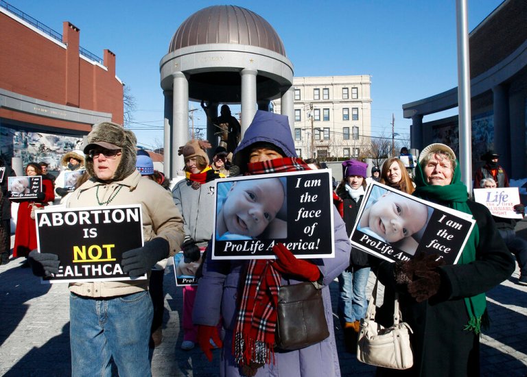 People are bundled against the bitter cold as they stand outside the New Jersey Statehouse Monday, Jan. 24, 2011, in Trenton, N.J., during an anti-abortion rally. The rally was one of many around the country held by abortion opponents on the 38th anniversary of Roe v. Wade, the landmark U.S. Supreme Court decision that legalized abortion. (AP Photo/Mel Evans)