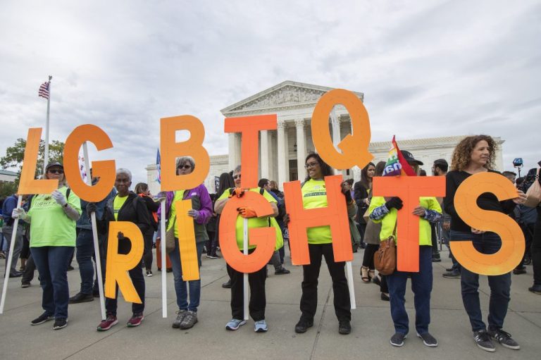 Supporters of LGBT rights hold placards in front of the Supreme Court